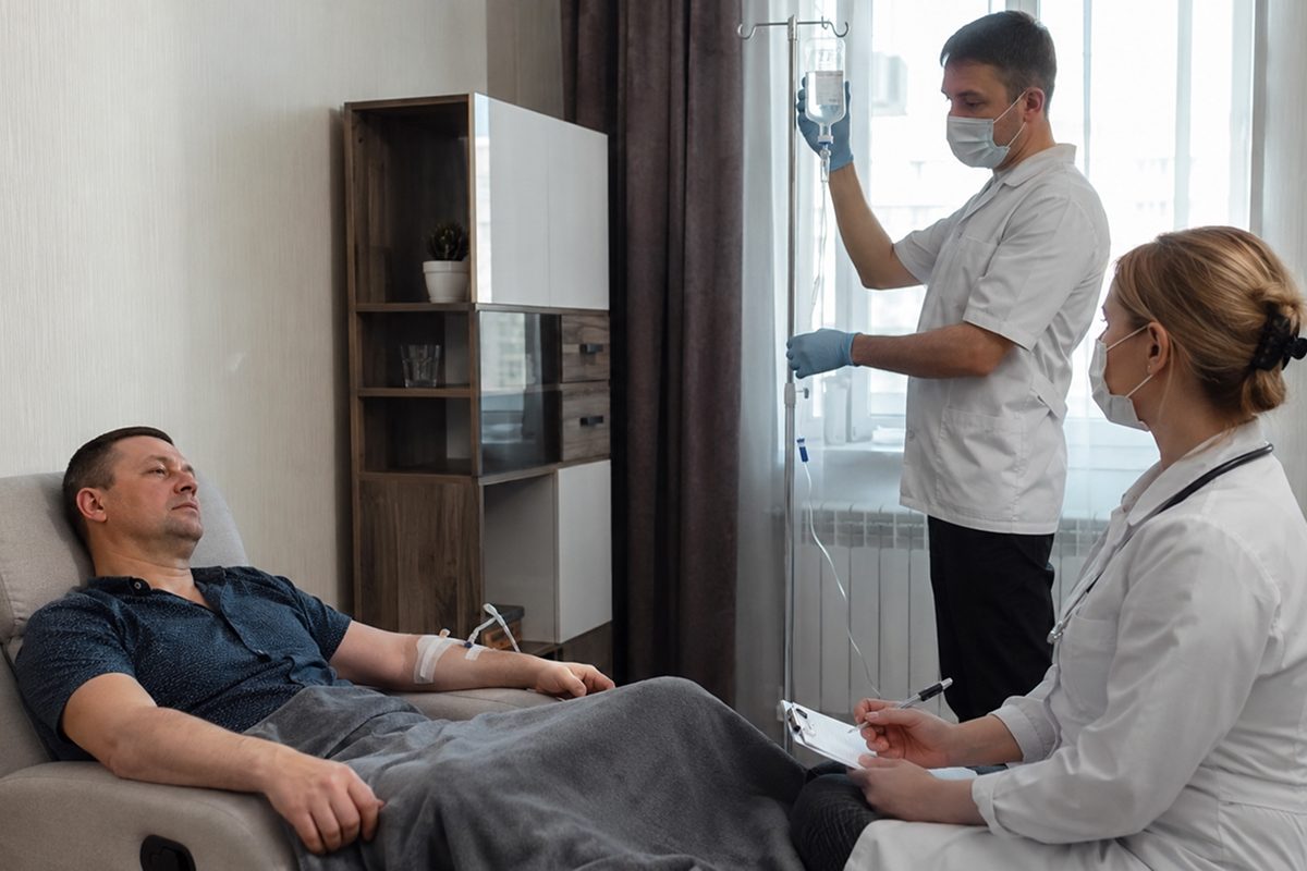 Доктор поправляет капельницу пациента